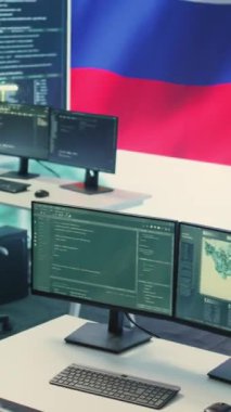 Büyük ekranda Rus bayrağı olan dikey video izleme ve hackleme odası siber casusluğu ve dijital manipülasyonu temsil ediyor. Rus hükümeti propaganda ve yanlış bilgilendirme üzerine çalışıyor.
