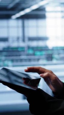 Dikey video sistemi yöneticisi sunucu odasını izliyor, kontrol yapıyor, gerekli düzeltmelerin tabletine veri giriyor. Veri merkezi depolama tesislerinde çalışan bilişim destek çalışanı