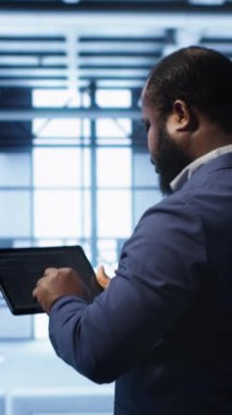 Veri merkezindeki dikey video bilimci hatayı düzeltmek için tablet üzerindeki araçları kontrol ederken hata yapıyor. Sunucu merkezi tesisinde IT uzmanı süper bilgisayarları etkileyen ağ sorunları arıyor