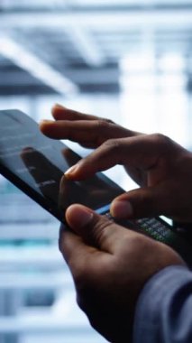 Dikey video yazılım geliştiricisi veri merkezi elektroniği ömrünü uzatmak için tablet kullanarak yıllık check-up yapıyor. Sunucu odasındaki çalışanın dijital kullanarak sunucu altyapısını izleme görüntüsünü kapat