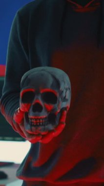 Dikey Görüntü: Manyak bir Rus hacker siber casusluk ve kötü niyetli kod kavramı olarak kafatasını tutarak siber tehdit uyarısı yapıyor. Siber güvenlik riskleri ve zararlı kötülükler hakkında yanılsama uyarısı