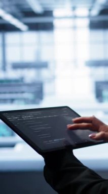 Dikey video sistemi yöneticisi veri merkezi ekipman ömrünü uzatmak için tablet kullanarak yıllık check-up yapıyor. Bilgi işlem uzmanının dijital kullanarak süper bilgisayarları izleme görüntüsünü kapat