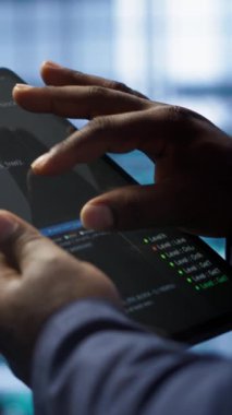 Dikey video yazılım geliştiricisi veri merkezi elektroniği ömrünü uzatmak için tablet kullanarak yıllık check-up yapıyor. Sunucu odasındaki çalışanın dijital kullanarak sunucu altyapısını izleme görüntüsünü kapat