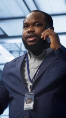 Veri merkezindeki dikey video bilgi işlem görevlisi telefonla konuşuyor, yıllık kontrol yapıyor. Telefon görüşmesi sırasında sunucu merkezinde yöneticiyle sohbet eden saha mühendisi, sunucuları izliyor