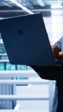 Yüksek teknolojili bir tesiste, sunucu dolaplarını etkileyen ağ sorunlarını çözmek için laptop kullanan dikey bilgisayar bilimci performansı ve bağlantıyı etkileyen zayıf istemci iletişimine, kamera B