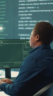 Bir hükümet güvenlik operasyon merkezinde çalışan dikey video siber savunma ekibi. Uzmanlar siber suçları önleme ve veri sızıntısı korumasını güvence altına alarak büyük ekranda bilgi inceliyorlar. Kamera.