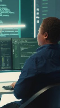 Dikey Video Hükümeti hackerları siber tehdit tespiti için verileri analiz ediyor, yüksek teknoloji ofisindeki büyük ekrana bakıyor. Siber istihbaratı, çevrimiçi güvenliği ve dijital ortamın önlenmesini vurgula