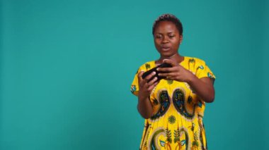 Mutlu kız online video oyunları yarışmasını kazanıyor, mavi arka plana karşı spor turnuvası oynarken eğleniyor. Kadın internet oyunu oynuyor, zaferini kutluyor. Kamera B.