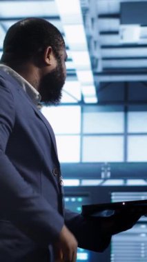 Veritabanı elektronik yaşam süresini uzatmak ve devre dışı kalmamak için not defteri kullanarak yıllık check-up yapan dikey video yönetimi. Adam sunucu odasına giriyor, sunucu altyapı bileşenlerini kullanarak izliyor