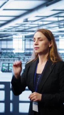 Veri merkezindeki hologramlara bakıp altyapıyı izleyen dikey video yazılım geliştiricisi. Sunucu odasındaki kadın yüksek teknolojili artırılmış gerçeklik yapay zekası ile etkileşimde, kamera B
