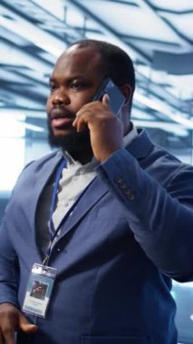 Veri merkezindeki dikey video bilgi işlem görevlisi telefonla konuşuyor, yıllık kontrol yapıyor. Telefon görüşmesi sırasında sunucu merkezinde yöneticiyle sohbet eden saha mühendisi, sunucuları izliyor