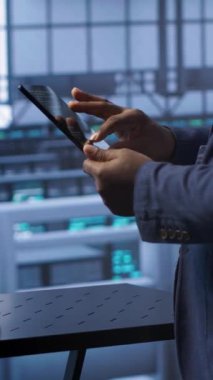 Sunucu merkezinde dikey video teknisyeni yeni yeni sipariş edilen depolama ünitesini kuruyor, parametreleri tabletle kontrol ediyor. Veri merkezi tutma aygıtı bilişim uzmanı, depolama ana bilgisayarlarının yerini alıyor