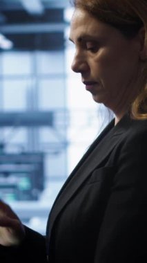 Dikey video teknisyeni check-up yapıyor, sunucu merkezindeki gerekli düzeltmelerin tabletine veri giriyor ve kritik bilişim iş yüklerini destekleyen gelişmiş veri depolama altyapısına ev sahipliği yapıyor, kamera A