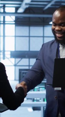 Dikey video Afrikalı Amerikalı yönetici karşılama müfettişi veri merkezine operasyonları denetlemek için geliyor. Sunucu merkezi çalışma alanı bilişim uzmanı denetleyici izleme performansı ile el sıkışma yapıyor
