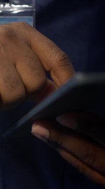 Sunucu merkezindeki dikey video teknisyeni tablet üzerindeki kurtarma planını kontrol ediyor ve ana bilgisayarlardaki enerji tüketimini izliyor. Veri merkezindeki adamın yakın plan görüntüsü. Platformların çalıştığından emin olmak için.