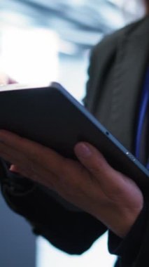 Dijital cihaz kullanarak ileri teknoloji ile veri merkezini yöneten dikey video programcısı. Kadının sunucu odasında yürürken yakın plan görüntüsü, veri merkezi teknolojisini tabletle optimize etmek, kamera B