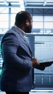 Veritabanı elektronik yaşam süresini uzatmak ve devre dışı kalmamak için not defteri kullanarak yıllık check-up yapan dikey video yönetimi. Adam sunucu odasına giriyor, sunucu altyapı bileşenlerini kullanarak izliyor