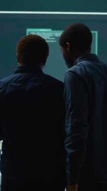 Bir hükümet kontrol odasında siber gözetleme yapan dikey video siber güvenlik ekibi. Yüksek teknoloji ajansında uzman grup hackleme faaliyetleri, kötü amaçlı yazılım koruması ve veri sızıntısını önleme