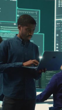 Hükümetin bilgisayar korsanlarından oluşan dikey video grubu büyük bir ekran kullanarak bilgisayar ağlarındaki dijital tehditleri analiz ediyor. Bilgi toplama, siber suçlara ve siber terörizme karşı savaşan uzmanlar