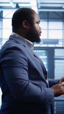 Dikey video teknisyeni sunucu odasında yürüyor, check-up yapıyor, ihtiyaç duyulan düzeltme tabletine veri giriyor. Bilgi İşlem Merkezi 'nde çalışan bilişim uzmanı konut depolama altyapısı, kamera B