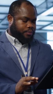 Veri merkezinde yürüyen dikey video bilişim teknisyeni, tablet kullanarak sunucu işlemlerini denetliyor. Dijital aygıt, kamera A kullanılarak sunucu merkezinde optimal performans ve veri bütünlüğü sağlama uzmanı