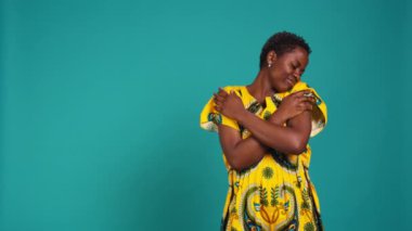 Afrikalı etnik kökenini temsil eden kendine güvenen genç bir kadın stüdyoda çiçekli bir kabile elbisesi giyerek. Doğuştan gelen kökleriyle gurur duyan tatlı doğal bir kız. Kamera B.