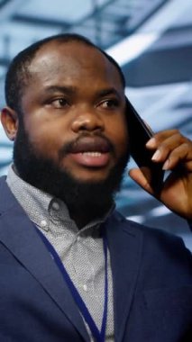 Veri merkezindeki programcının telefon görüşmeleri ve teftiş yaparken çekilmiş dikey görüntüsü. Sahada bilişim uzmanı, telefon görüşmesi sırasında sunucu merkezinde yöneticiyle konuşuyor.