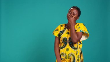 Stüdyoda mavi arka planda kıkırdayan sevimli bir kadın model, kabile kültürünü sembolize etmek için çiçek desenli elbiseler giyiyor. Mutlu kendine güvenen kız gülüşü, doğal güzellik. Kamera B.