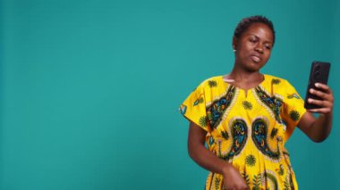 Çevrimiçi bir video çağrısına cevap veren, web kamerasına gülümseyen ve arkadaşlarıyla tartışan kendinden emin mutlu bir insan. Mavi arkaplana karşı uzak video konferans ağı. Kamera B.