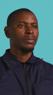 Siyahi stüdyo geçmişiyle izole edilmiş Afrikalı Amerikan güvenlik ajanının dikey video portresi. Gardiyanın, stüdyo arkaplanının önünde dikilirken yakın plan çekimi, kamera B