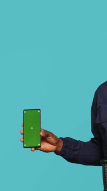 Güvenlik ajanının dikey video portresi sahte telefon sunumu ve atama görevi, stüdyo geçmişi. Güvenlik ihlalleriyle uğraşırken yeşil ekran akıllı telefonu gösteren gardiyan