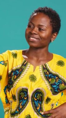 Dikey Video Büyüleyici doğal kadın özgüven pozu veriyor, mavi arka planda akıllı telefonuyla fotoğraf çekiyor. Genç adam stüdyoda fotoğraf çekiyor. Kamera A.