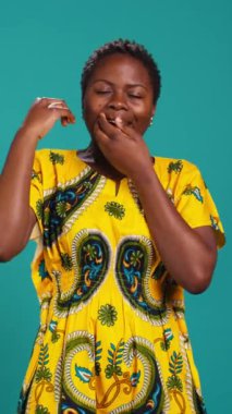 Dikey Video Yorgunluğu çeken kız stüdyoda uykusuzluk çekiyor, esniyor ve mavi arka planda son derece yorgun. Yorgun bir kadın kendini çok yorgun ve tembel hissediyor. Kamera B.