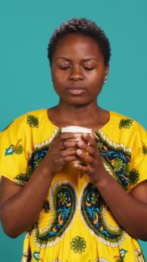 Dikey Video Neşeli, mavi arka planda bir fincan kahve içen neşeli kişi, stüdyoda kızarmış aroma ve tazeliğin tadını çıkarıyor. Kafein servisi yapan tatmin olmuş bir kadın. Kamera A.