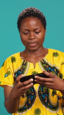 Dikey Video Heyecanlı iyimser kız video oyunlarındaki zaferini stüdyoda kutluyor, akıllı telefonuyla online mobil oyunlar oynuyor. Mutlu kadın oyuncu siber spor şampiyonluğu kazanıyor. Kamera A.