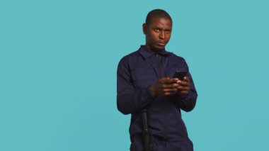 Güvenlik görevlisi akıllı telefon kullanıyor, koruma görevi sırasında mola veriyor. İş yerindeki arkadaşlarına cep telefonuyla mesaj atan korumaların portresi, stüdyo arka planında izole edilmiş, kamera B