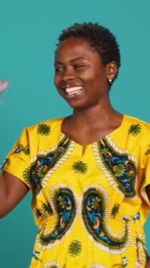 Dikey Video Tatlısı kadın parmaklarını şaklatarak ritmi tutturuyor, dans ediyor ve stüdyoda hareket ediyor. Geleneksel yerli kıyafetleri içinde hoş bir kız. Havalı ve havalı davranıyor. Dans hareketleri yapıyor.