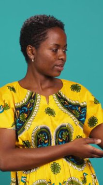 Stüdyoda sağa ya da sola işaret eden ve işaret parmaklarını sağa sola gösteren dikey, kendine güvenen kız. Genç doğal insan geleneksel Afrika kıyafetleri giyer.