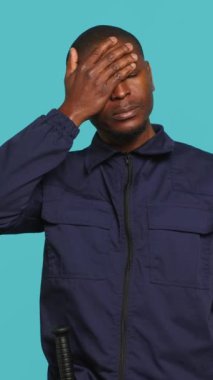 Yorgun güvenlik görevlisinin evle ilgilenirken baş ağrısından muzdarip dikey video portresi. Özel polis memuru yorgunluk, stüdyo arkaplanı ve kamera A 'dan dolayı acı çekiyor.