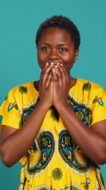 Dikey Video Şaşkınlığı genç bir kadın bazı iyi haberler alıyor ve mutlu hissediyor, stüdyodaki bir şeyden memnun. Afro etnik giysiler içinde gülümseyen olumlu insan, iyimser kız. Kamera A