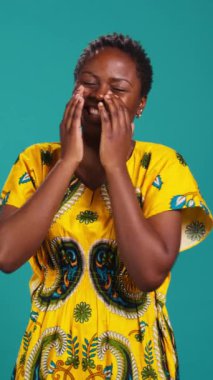 Dikey Video Feminen doğal genç kız stüdyoda bir şeye gülüyor, geleneksel bir şekilde giyiniyor ve çiçekli şeyler giyiyor. Etnik geleneği kıyafetlerle temsil eden kendinden emin bir kadın.