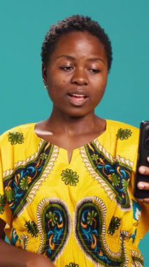 Dikey Video Güvenilir Mutlu Kişi çevrimiçi bir video çağrısına cevap verir, webcam 'e gülümser ve arkadaşlarıyla tartışır. Mavi arkaplana karşı uzak video konferans ağı. Kamera A.