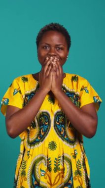 Dikey Video Şaşkınlığı genç bir kadın bazı iyi haberler alıyor ve mutlu hissediyor, stüdyodaki bir şeyden memnun. Afro etnik giysiler içinde gülümseyen olumlu insan, iyimser kız. Kamera B