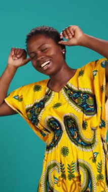 Dikey Video Oynayan, dilini dışarı çıkaran ve stüdyoda aptalca davranıp eğlenen sevimli kız. Kendine güveni tam komik bir kadın mavi arka planda şakalar yapıyor, aptallık ediyor. Kamera B.