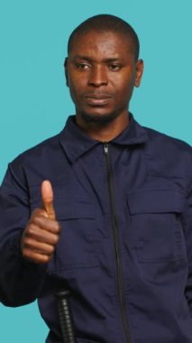 Dikey güvenlik görevlisi parmaklarıyla işaret işareti yapıyor. Yasak bölgeye kamu erişimini engelliyor. Gülümseyen korumanın portresi olumlu el hareketi yapıyor, stüdyo