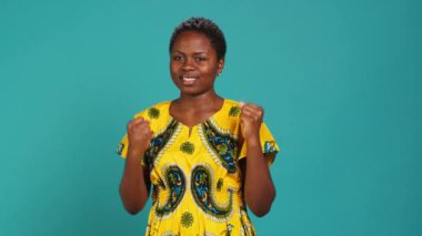 Mutlu bir kadın başına iyi bir şey gelmesini umuyor. Stüdyoda tezahürat yapıyor ve umutlu. Özgüvenle poz veren pozitif gülümseyen genç bir yetişkin. Kamera A.