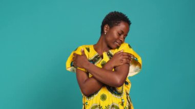 Afrikalı etnik kökenini temsil eden kendine güvenen genç bir kadın stüdyoda çiçekli bir kabile elbisesi giyerek. Doğuştan gelen kökleriyle gurur duyan tatlı doğal bir kız. Kamera A.