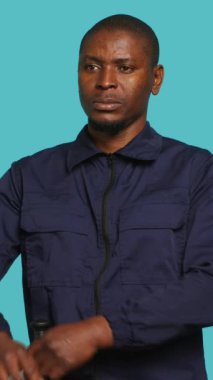 Stüdyonun arka planında izole edilmiş gülen güvenlik ajanının dikey görüntüsü. Afrika kökenli Amerikalı gardiyanlar güvenlik ihlali ve gerginliği azaltmaya hazırlanıyorlar.