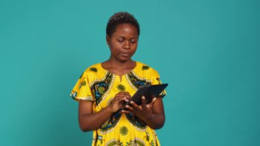 Stüdyoda sosyal medya platformlarını kontrol eden genç bir kadın internet sitelerini mavi arka planla karşılaştırıyor. Geleneksel yerli kıyafetleriyle poz veren doğal tatlı kız. Kamera A.