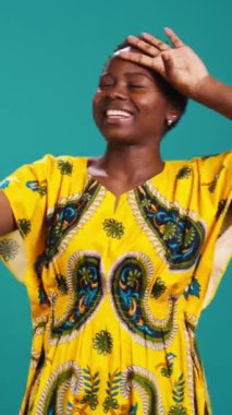 Dikey Video Büyüleyici doğal kadın özgüven pozu veriyor, mavi arka planda akıllı telefonuyla fotoğraf çekiyor. Genç adam stüdyoda fotoğraf çekiyor. Kamera B.